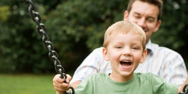 Father pushing son on swing