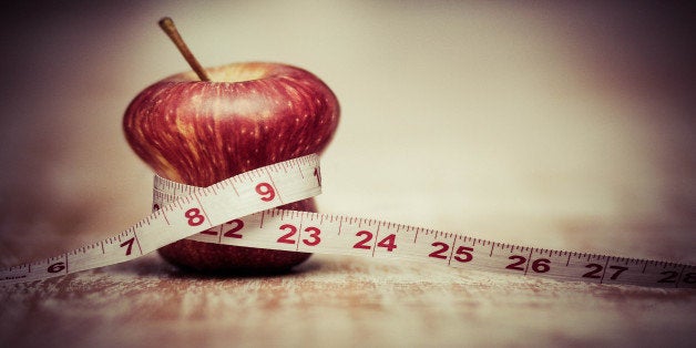 A manipulated photo of an apple squeezed by a measuring tape, diet, restrictions, weightless, lose weight, health, maintaini