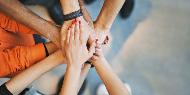 Multiethnic group of young people putting their hands on top of each other. Close up image of young students making a stack o