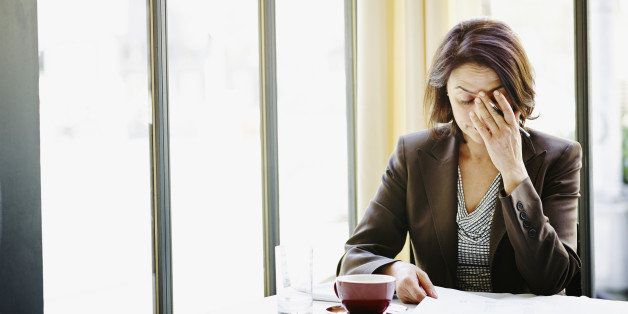 Businesswoman sitting at table in restaurant with head resting on hand