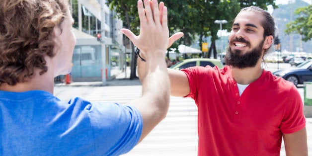 Man with beard give high five to caucasian guy outdoor in the city