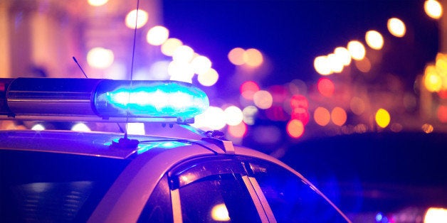 Blue light flasher atop of a police car. City lights on the background. 