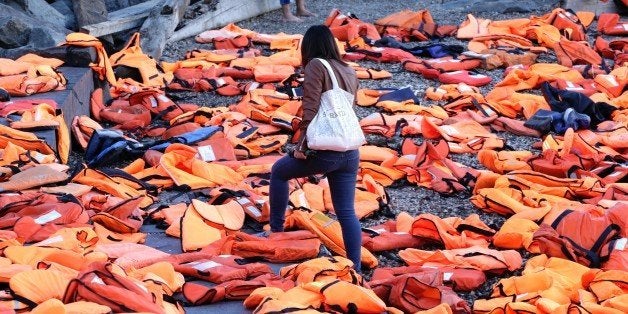 TOPSHOT - A woman walks through life jackets which have been collected from the beaches of Chios, Greece and used by adults a