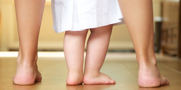 Close up portrait of a mother helping baby to walk indoors