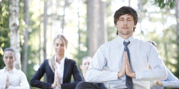 Business people practicing yoga in park