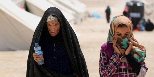 In this picture taken Saturday, June 25, 2016, internally displaced woman and her daughter from Fallujah, who fled their homes during fighting between Iraqi security forces and the Islamic State group, at a camp at Amariyat Fallujah, Iraq. Tens of thousands of Iraqis who survived a harrowing flight from Fallujah now find themselves in sprawling desert camps with little food, water or shelter. The growing humanitarian crisis less than an hourâs drive from Baghdad has reinforced the regionâs deep-seated distrust of the government, and could undermine recent gains against the Islamic State group. (AP Photo/ Khalid Mohammed)