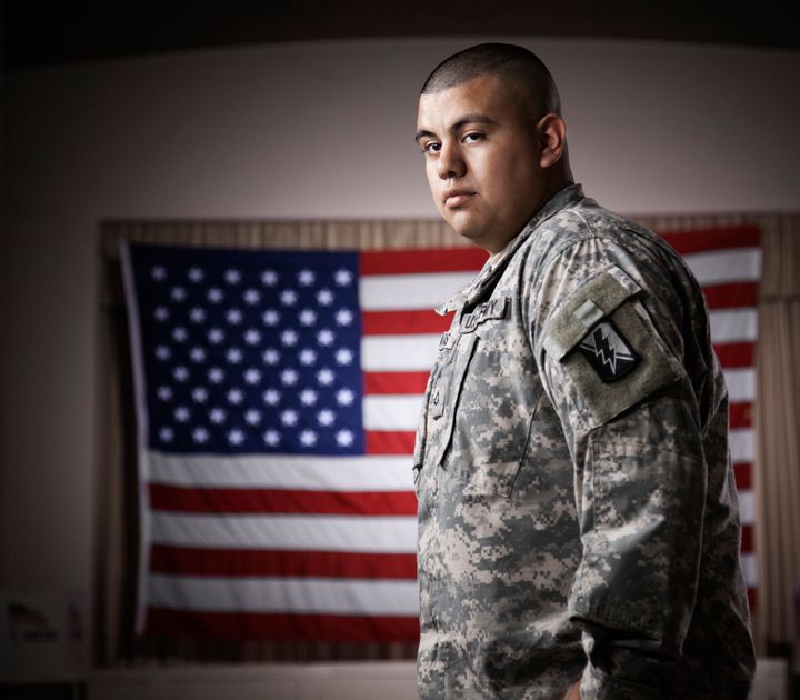 Hispanic soldier standing in front of American flag