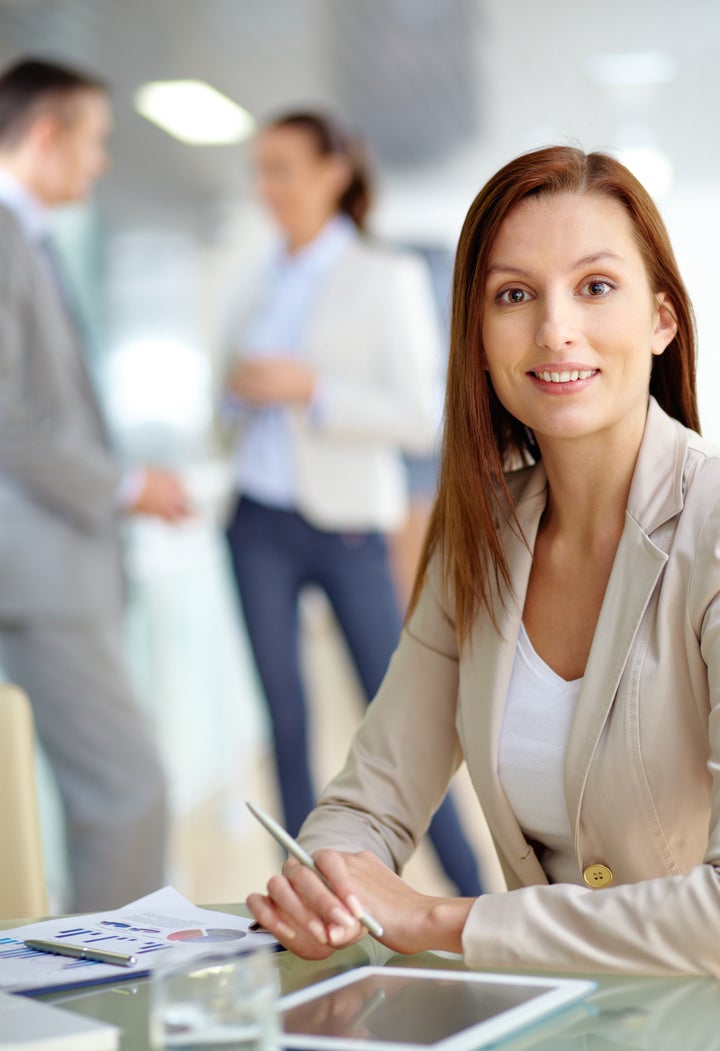 Portrait of friendly specialist looking at camera on the background of working colleagues