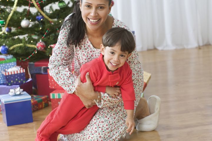 Mom sitting in front of Christmas tree holding her young son