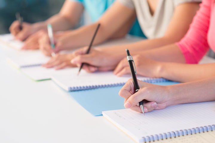 Close-up of writing hands of students at school