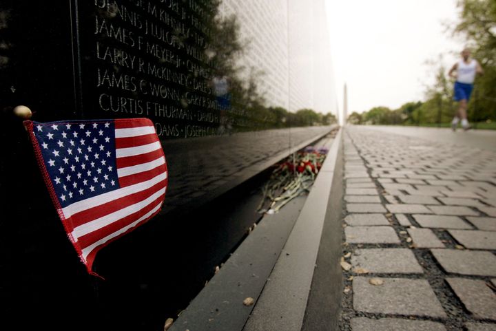 WASHINGTON - APRIL 29: An early morning jogger runs past an American flag left in remembrance to Americans killed in Vietnam at the Vietnam Veterans Memorial on April 29, 2005 in Washington DC. April 30 marks the 30th anniversary of the fall of Saigon and the end of the war. (Photo by Win McNamee/Getty Images)