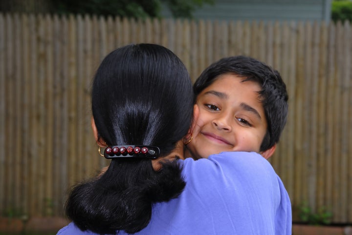 a happy indian kid hugging his...