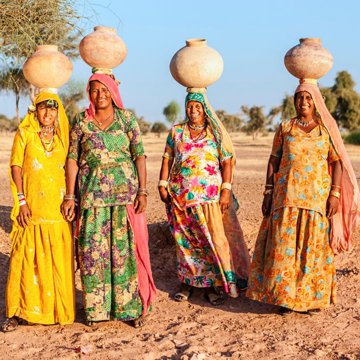 Indian women carrying water from the lake. Collecting and carrying water are women's responsibilities in India. Rajasthani wo