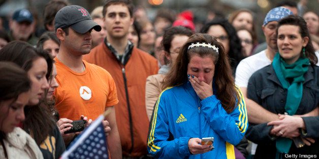 A woman, wearing a Boston Marathon 2013 jacket, cries as people gather in the Boston Commons for a vigil on April 16, 2013 in Boston, in the aftermath of two explosions that struck near the finish line of the Boston Marathon on April 15. Investigators said the range of suspects and motives in the grisly Boston bombings remained 'wide open' as experts assessed remnants of the crude devices designed to inflict maximum suffering. AFP PHOTO/Don Emmert (Photo credit should read DON EMMERT/AFP/Getty Images)