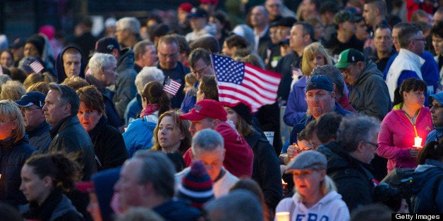 Mourners hold candles and U.S. flags during a vigil for Martin Richard, one of three killed in the Boston Marathon bombings, at Garvey Park in Boston, Massachusetts, U.S., on Tuesday, April 16, 2013. Richard, an 8-year-old from Boston's Dorchster neighborhood, was among the dead in blasts that also injured his mother and sister. Photographer: Scott Eisen/Bloomberg via Getty Images