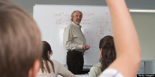 Boy (7-9) raising hand in class, rear view