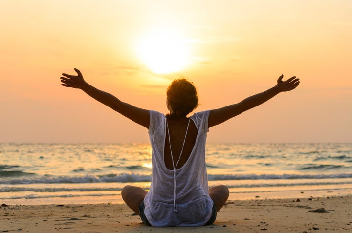 young woman is sitting on beach at sunrise