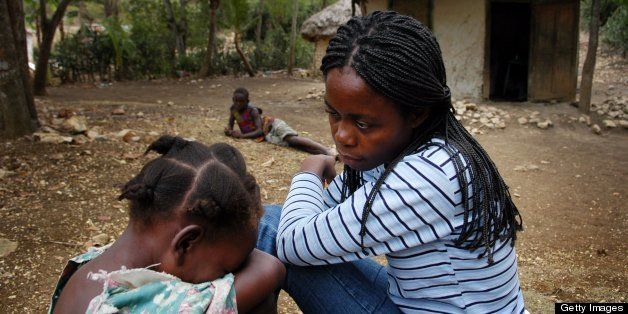 HAITI - APRIL 11: Seven-year-old Meloude Casseus, a former 'restavek', weeps while being soothed by social worker Pasqual, at Meloude's family home on April 11, 2005 in a rural village near Les Cayes, Haiti. Meloude was returned to her biological parents after she was found running through a Port-au-Prince street, apparently badly beaten, but her family plans to give her to another family that they hope will take better care of her. Hundreds of thousands very young children have been handed over to 'host' families in Port-au-Prince by desperately poor parents lured by the promise of a better life. Instead, the children receive no education and are forced to do hard, menial jobs; oftentimes they are forbidden to join the host family for meals, and sleep on concrete or dirt floors with little clothing. When they reach 15-years of age (by law the age to recieve a wage), families often throw restaveks out to the street and replace them with younger children. These children are called 'restavek,' which in the local Creole language means, 'to stay with.' (Photo by Shaul Schwarz/Getty Images)