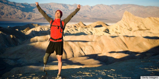 An athlete with a prosthetic leg celebrating with arm raised high.