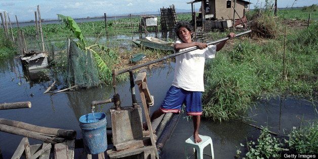 Water And Sanitation, Philippines, Cebu City, Woman Collecting Water From A Submerged Standpipe, These families are too poor to buy homes inland with access to clean water, They are forced to build make shifthouses along estuaries which are flooded for six to eight months a year, There is no sanitation system and rubbish is dumped in the water, Many people in the community are affected by disease, (Photo by Universal Images Group via Getty Images)