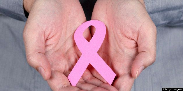 Woman holding breast cancer ribbon symbol in her hands.