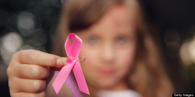 Girl holding pink ribbon, symbol of breast cancer.