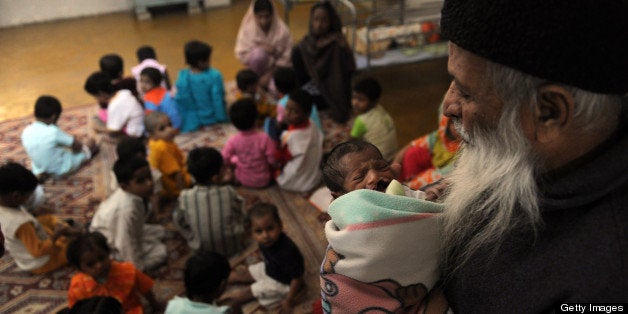 TO GO WITH AFP STORY IN FRENCH BY Hasan Mansoor 'Pakistan-enfants-femmes-violences,PREV'In this photograph taken on December 6, 2010 Abdul Sattar Edhi, head of Pakistani's Edhi foundation holds a disabled orphanat the orphanage of the charity in Karachi. In the conservative Muslim nation, where the birth of children outside of marriage is condemned and adultery is a crime punishable by death under strict interpretations of Islamic law, infanticide is a crime on the rise. AFP PHOTO/ RIZWAN TABASSUM (Photo credit should read RIZWAN TABASSUM/AFP/Getty Images)