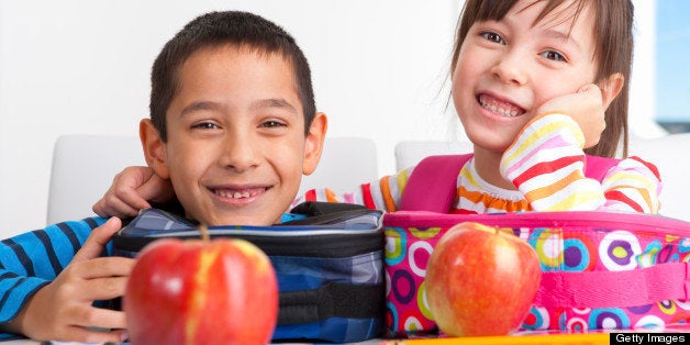 8 year old boy and 6 year old girl eating an apple before heading to school