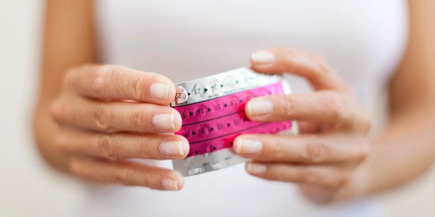 Woman's hand holding birth control pills, cropped