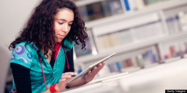 Young woman in the library surfing the net with digital tablet.