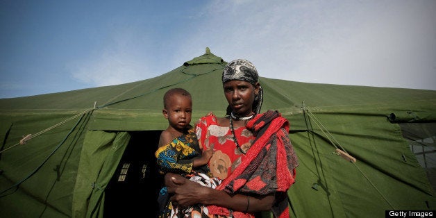 RESTRICTED TO EDITORIAL USE - MANDATORY CREDIT 'AFP PHOTO / AU-UN IST / STUART PRICE' - NO MARKETING NO ADVERTISING CAMPAIGNS - DISTRIBUTED AS A SERVICE TO CLIENTS A Somali woman and her malnourished baby emerge from a tent serving as a medical clinic which was established by the African Union peacekeeping mission in Somalia (AMISOM), in Mogadishu, on July 16, 2011. The mission's Civil-Military Component (CIMIC) has built five large waterproof tents in a camp for internally displaced people near the the city's airport to serve as accommodation and a medical centre, with Ugandan doctors serving with the mission offering free medical treatment for people affected and displaced by the drought currently ravaging Somalia and the wider Horn of Africa region. AFP PHOTO / AU-UN IST PHOTO / STUART PRICE. (Photo credit should read STUART PRICE/AFP/Getty Images)