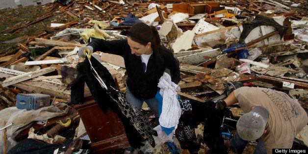 Kalissa Graham retrieves her belongings from her destroyed home with the help of her friend Derick Colwell on May 21, 2013 in Moore, Oklahoma. Families returned to a blasted moonscape that had been an American suburb Tuesday after a monstrous tornado tore through the outskirts of Oklahoma City, killing at least 24 people. Nine children were among the dead and entire neighborhoods vanished, with often the foundations being the only thing left of what used to be houses and cars tossed like toys and heaped in big piles. AFP PHOTO/Joshua LOTT (Photo credit should read Joshua LOTT/AFP/Getty Images)