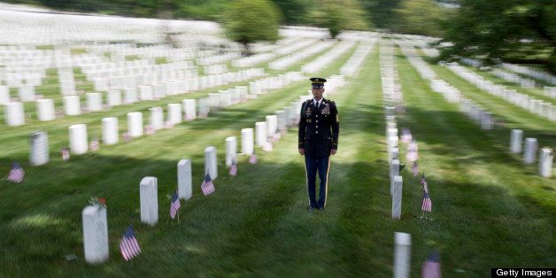 A member of the honor guard stands at attention as the motorcade with U.S. President Barack Obama passes during Memorial Day activities at Arlington National Cemetery in Arlington, Virginia, U.S., on Monday, May 27, 2013. U.S. President Barack Obama stepped into the role of consoler-in-chief today, as he laid a wreath at Arlington National Cemetery to honor fallen troops and called on Americans not to forget the war in Afghanistan. Photographer: Joshua Roberts/Bloomberg via Getty Images