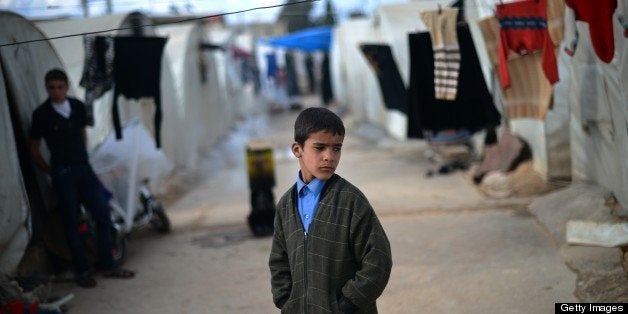 An internally displaced Syrian boy stands near tents in the Maiber al-Salam refugee camp along the Turkish border in the nort