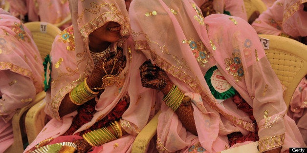 Indian Muslim brides chat as they wait for the start of a mass wedding ceremony in Ahmedabad on November 4, 2012. Some 47 Muslim couples participated in a mass wedding ceremony organised by The Fazale Rabbi Samuh Lagna Committee. AFP PHOTO/Sam PANTHAKY (Photo credit should read SAM PANTHAKY/AFP/Getty Images)