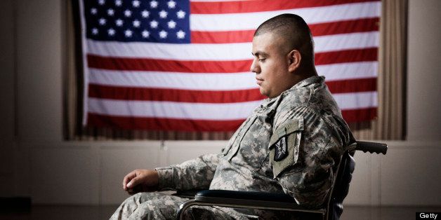 Hispanic soldier in wheelchair near American flag