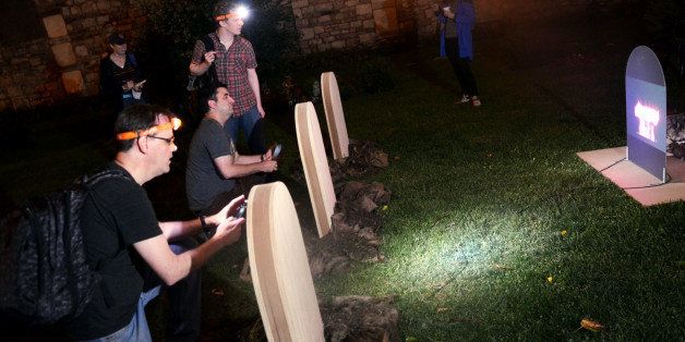 Ken Vogel, from left at tombstones, Greg Jensen and Ryan Hendrickson, employees of the hedge fund Bridgewater Associates Inc., take on a challenge that requires rhythm and knowledge of the band Queen, at New York Marble Cemetery during Midnight Madness, an all-night puzzle hunt in New York, U.S., on Sunday, Oct. 6, 2013. The final results for the event went out via e-mail today. Photographer: Amanda Gordon/Bloomberg via Getty Images 