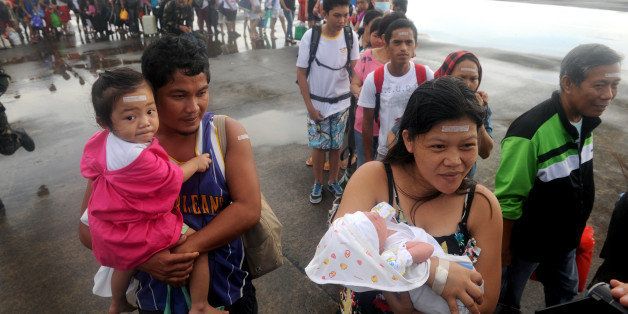 Typhoon survivor Rosel Honrado (R), 24, carries her one-day-old son Ian Daniel as they take a flight on a C-130 military plane out of Tacloban, Leyte province, central Philippines Tacloban, Leyte province, central Philippines on November 13, 2013. The US military has ordered two amphibious ships to the Philippines to help victims of the devastating Typhoon Haiyan and a third was poised to deploy, officials said Tuesday. The move will ferry hundreds of US Marines to the storm-ravaged country as well as vehicles able to operate in flooded, debris strewn areas, officials said. AFP PHOTO/NOEL CELIS (Photo credit should read NOEL CELIS/AFP/Getty Images)