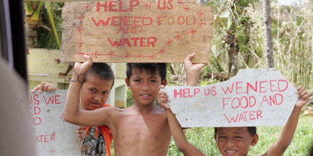 GUIUAN, EASTERN SAMAR, PHILIPPINES - NOVEMBER 20: Children hold placards as they appeal for help with motorists following the recent super typhoon on November 20, 2013 near Guiuan, Eastern Samar, Philippines. Typhoon Haiyan, which ripped through the Philippines on November 9, has been described as one of the most powerful typhoons ever to hit land, leaving thousands dead and hundreds of thousands homeless. Countries all over the world have pledged relief aid to help support those affected by the typhoon, however damage to the airport and roads have made moving the aid into the most affected areas very difficult. With dead bodies left out in the open air and very limited food, water and shelter, health concerns are growing. (Photo by Jeoffrey Maitem/Getty Images)