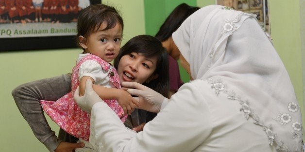 TO GO WITH STORY by Arlina ARSHADThis picture taken in Bandung on February 10, 2013 shows an Indonesian toddler (L) with her mother preparing to have a circumcision in Bandung. After the United Nations in December passed a resolution banning female genital mutilation (FGM), Indonesia, home to the world's biggest Muslim population, is trying to defend the long tradition, claiming female circumcision is not a mutilation. AFP PHOTO / ADEK BERRY (Photo credit should read ADEK BERRY/AFP/Getty Images)