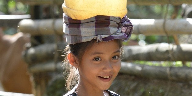 TO GO AFP WITH STORY INDONESIA-SOCIAL-INDIGENOUS-TRADITION BY OLIVIA RONDONUWUThis picture taken on August 12, 2013 shows a Kajang girl carrying a bucket of water at Amatoa village where the Kajang tribe live in Bulukumba, South Sulawesi. Deep in a remote forest in the Indonesian archipelago, the Kajang tribe lives much as it has done for centuries, resisting nearly all the trappings of modern life. AFP PHOTO / ADEK BERRY (Photo credit should read ADEK BERRY/AFP/Getty Images)