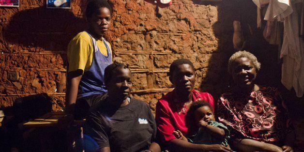Helen (2nd L) and Diana Tutyanabo (L) with with their mother (R) and another unidentified relative pose at their home in the Kataanga slum of the Ugandan capital Kampala on December 4, 2012. Helen, 23, along with her younger sister Diana, 20, living in a trash ridden slum area, are two young women who stand out amongst their neighbours as they both are professional boxers, literally trying to fight their way out of poverty. After a man tried to rape Helen, the older of the two sisters, it inspired her to learn how to fight inorder defend herself, and despite recently winning a medal in an East African Regional Championship, Helen and Diana still have to collect garbage to sell to get money for food for themselves and nearly 20 other people, cramped into two rooms with no water or electricity. AFP PHOTO/Michele Sibiloni. (Photo credit should read MICHELE SIBILONI/AFP/Getty Images)