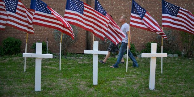 KILLEEN, TX - APRIL 3:Brandon Dunn of Baton Rouge, La, and Elissa Landry (blocked by flag) of Phoenix, Az, visit a memorial at the Central Christian Church, where three crosses have been erected for dead victims and 16 U.S. flags for those wounded in the latest Fort Hood shooting on Thursday, April 3, 2014, in Killeen, TX. Soldier Ivan Lopez killed three people and injured 16 others before turning the gun on himself on Wednesday. Both Dunn and Landry are enlisted in the Army and Dunn knows one of the victims who was shot and lived. (Photo by Jahi Chikwendiu/The Washington Post via Getty Images)