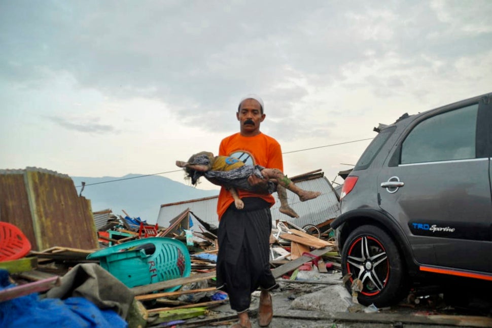 A man carries the body of a child who was killed in the tsunami in Palu.<i></i><i></i>