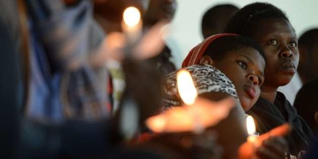 Rwandan women hold candles during a night vigil and prayer for genocide victims at the Amahoro stadium in Kigali, Rwanda, on