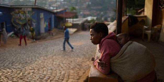 A woman stands on her porch at a suburb set on a hill overlooking Kigali, on March 13, 2014. Twenty years after the genocide