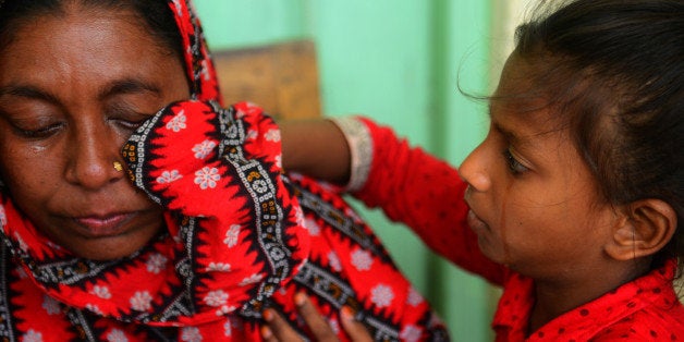 A Bangladeshi child wipes tears from her mother, that lost relatives believed to be trapped in the rubble of an eight-storey