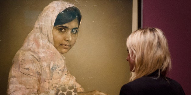 A gallery worker poses with a painted portrait of Malala Yousafzai, the teenage Pakistani advocate for girls education who wa
