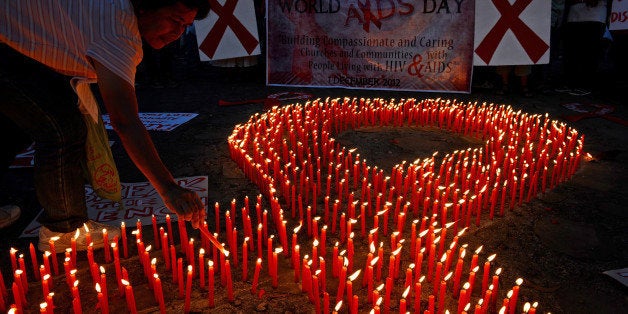 An AIDS activist lights a group of candles placed in the shape of a red ribbon during an event marking World Aids Day in Mani