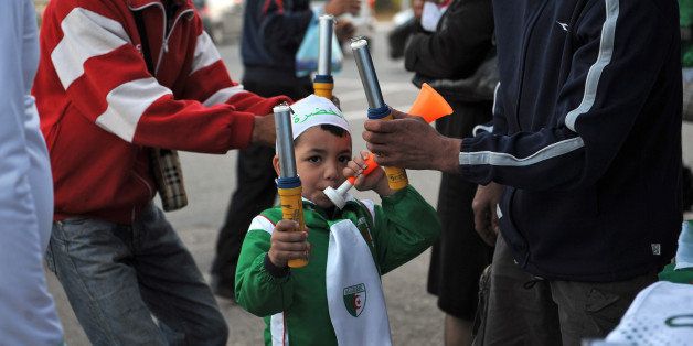 TO GO WITH AFP STORY BY PIERRE-YVES JULIEN An Algerian boy blows in a toy on November 12, 2009 as he stands by a street seller stand where are displayed Algerian flags and national football team jerseys, on the eve of their World Cup 2010 qualifying football match against Egypt. AFP PHOTO/ FAYEZ NURELDINE (Photo credit should read FAYEZ NURELDINE/AFP/Getty Images)